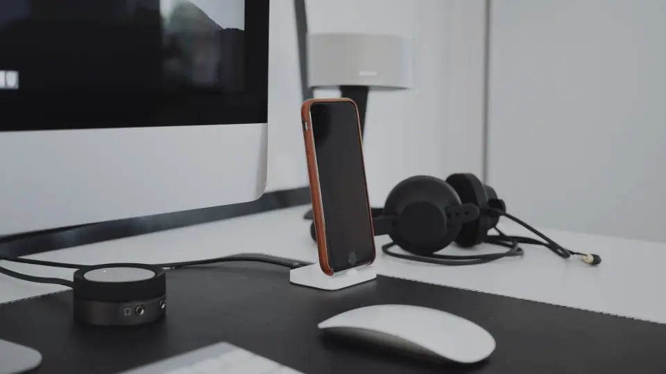 Escritorio con computadora, auriculares y celular, puesto típico de un equipo de ventas