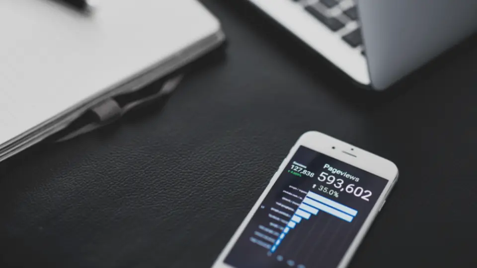 Celular con un gráfico de resultados junto a una notebook